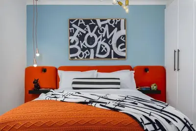 an orange bed with a black and white blanket at The Tram Stop in Franschhoek