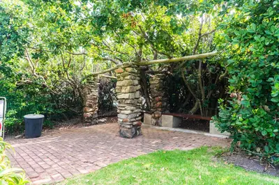 a stone archway with a bench in a garden at Bayview 305A in Hermanus