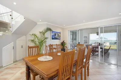 a dining room with a wooden table and chairs at Villa Kyma in Gordonʼs Bay