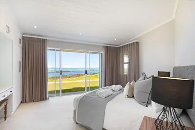 a bedroom with a bed and a view of the ocean at Villa Kyma in Gordonʼs Bay