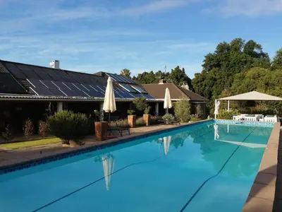 a swimming pool in front of a house at Gästehaus HelderbergView in Somerset West