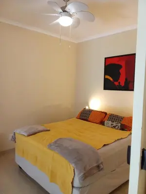 a bedroom with a yellow bed with a ceiling fan at Gästehaus HelderbergView in Somerset West