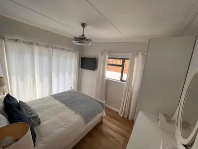a bedroom with a bed and a window at Adorable 2 Bedroom Cottage with spacious veranda in Hermanus