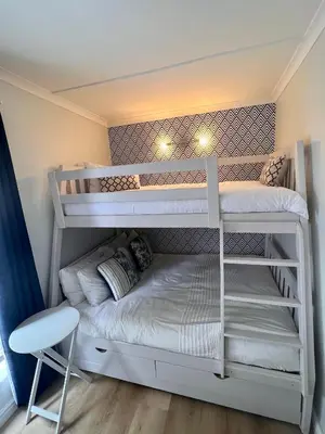 a white bunk bed in a room with a chair at Adorable 2 Bedroom Cottage with spacious veranda in Hermanus