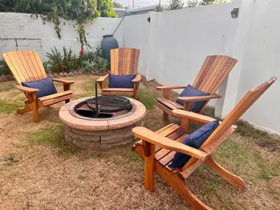 three rocking chairs sitting around a fire pit at Adorable 2 Bedroom Cottage with spacious veranda in Hermanus