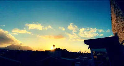 a sunset over a city with the sun in the sky at Kwaaami in Cape Town