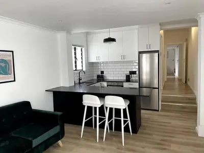 a kitchen with a black counter top and stools at Centrally located modern 2-bedroom home & parking in Cape Town
