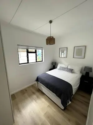 a white bedroom with a bed and a window at Centrally located modern 2-bedroom home & parking in Cape Town