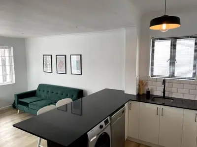a kitchen with a green couch in a living room at Centrally located modern 2-bedroom home & parking in Cape Town