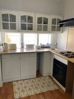 a kitchen with white cabinets and a kitchen rug at Johan-nest in Cape Town