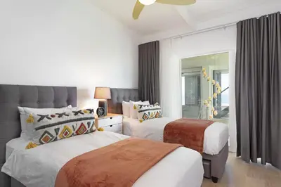 a bedroom with two beds and a mirror at Atlantic Sky Villa in Gordonʼs Bay
