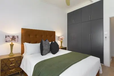 a bedroom with a large bed with black cabinets at Atlantic Sky Villa in Gordonʼs Bay