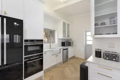 a kitchen with white cabinets and black appliances at Atlantic Sky Villa in Gordonʼs Bay