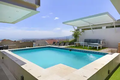a swimming pool with a view of a house at Atlantic Sky Villa in Gordonʼs Bay