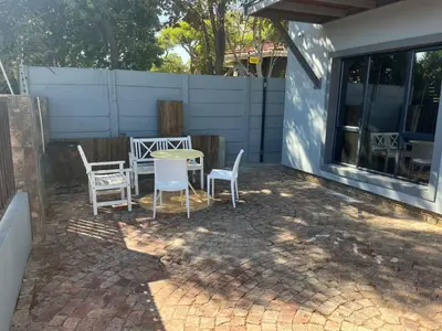 a patio with a table and chairs and a fence at The Elephant House in Cape Town