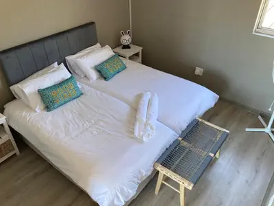 a large white bed with pillows and a chair in a bedroom at The Elephant House in Cape Town