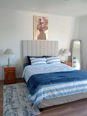 a bedroom with a large bed with a blue and white blanket at The Wee Hoose in Strand