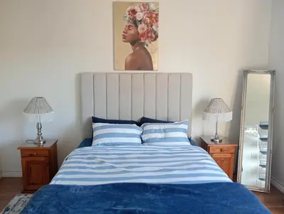 a bedroom with a bed with a painting on the wall at The Wee Hoose in Strand