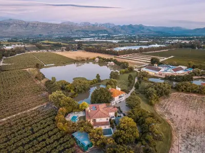 an aerial view of a estate with a lake and vineyards at Dawn Mountains Farm in Simondium