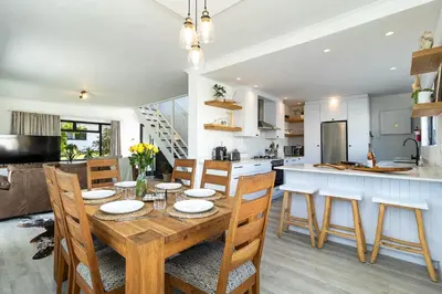 a kitchen and dining room with a wooden table and chairs at SAM's - Sea And Mountain in Hermanus