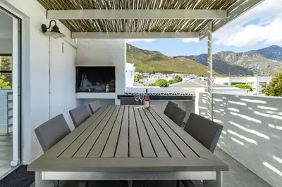 a wooden table and chairs on a patio with a fireplace at SAM's - Sea And Mountain in Hermanus