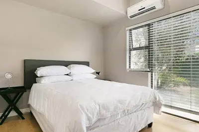 a bedroom with a large white bed and a window at On 8th Green Worthing Villa in Cape Town