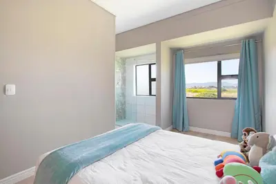 a bedroom with a bed with toys and a window at On 8th Green Worthing Villa in Cape Town