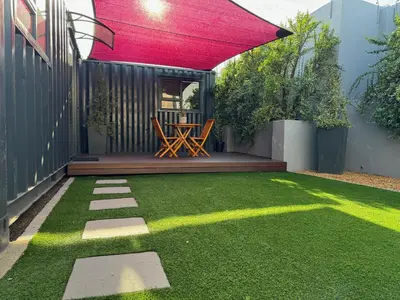 a patio with a lawn with a table and a red umbrella at The Leopard Leaf Inn in Cape Town