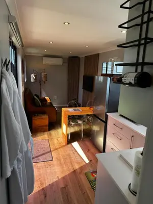 a kitchen with a refrigerator and a living room at The Leopard Leaf Inn in Cape Town