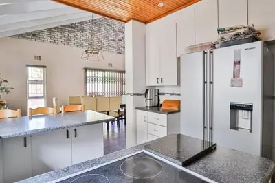 a kitchen with white cabinets and a refrigerator at Fairview Crescent by CTHA in Cape Town