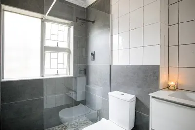 a bathroom with a toilet and a sink and a window at Fairview Crescent by CTHA in Cape Town