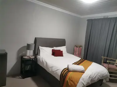 a bedroom with a bed with a red pillow on it at Maseyi On 8 bnb in Cape Town