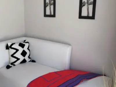 a white bed with a red blanket and two pictures at Maseyi On 8 bnb in Cape Town