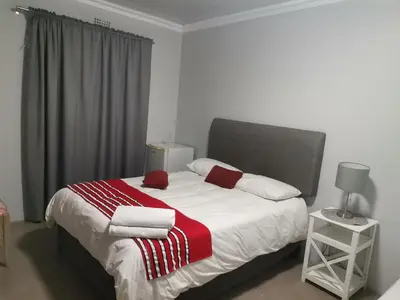a bedroom with a bed with a red and white blanket at Maseyi On 8 bnb in Cape Town
