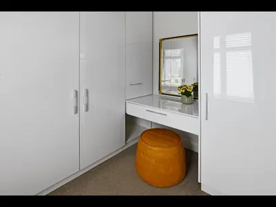 a white dressing room with a mirror and an orange stool at The Village Cottage in Franschhoek