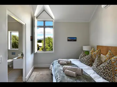 a bedroom with a bed with pillows and a window at The Village Cottage in Franschhoek