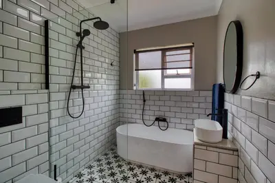 a white bathroom with a tub and a window at Magnificent Villa Load-Shedding Free! in Cape Town