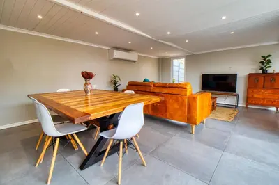 a dining room with a wooden table and a couch at Magnificent Villa Load-Shedding Free! in Cape Town