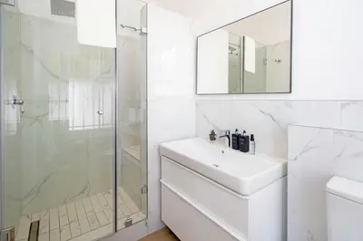 a white bathroom with a sink and a shower at Middedorp Manor in Stellenbosch