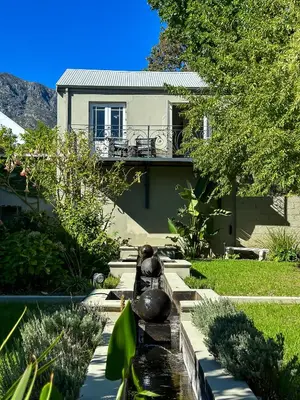 a house with a water fountain in front of a house at Loft de L'Opera - Franschhoek in Franschhoek