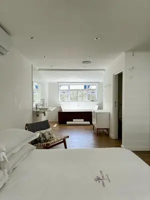 a white bedroom with a bed and a bathroom at Riebeeck Villa - 5 min walk to Franschhoek Central in Franschhoek
