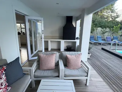 a porch with a couch and chairs on a deck at Riebeeck Villa - 5 min walk to Franschhoek Central in Franschhoek