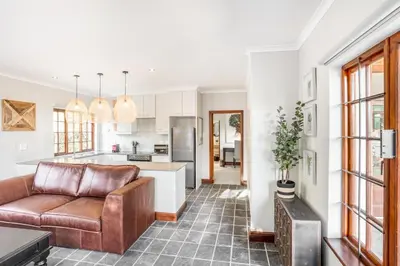 a living room with a couch and a kitchen at Avemore Olive Apartment - full Backup power in Stellenbosch