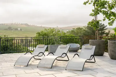 a group of white chairs sitting on a patio at Avemore Olive Apartment - full Backup power in Stellenbosch