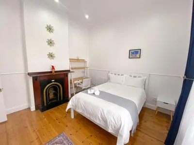 a bedroom with a white bed and a fireplace at Modern 8 Sleeper home in trendy Observatory in Cape Town