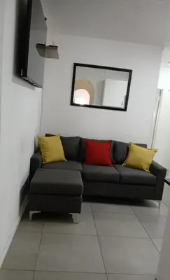 a black couch with yellow and red pillows in a room at Modern 8 Sleeper home in trendy Observatory in Cape Town