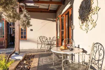 a patio with chairs and a table and a chandelier at Avemore Orchard Apartment - with full Backup power in Stellenbosch