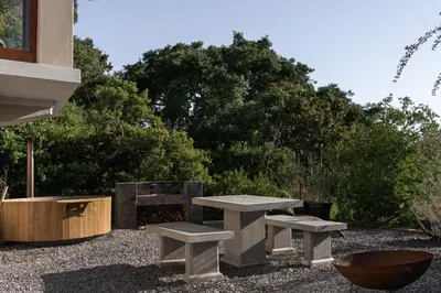 a picnic table and two benches in a yard at Avemore Hidden Haven - wood fired hot tub and full Backup power in Stellenbosch