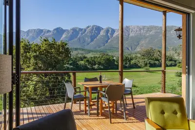 a deck with a table and chairs and a view of mountains at Tulbagh Mountain Bungalow in Wolseley