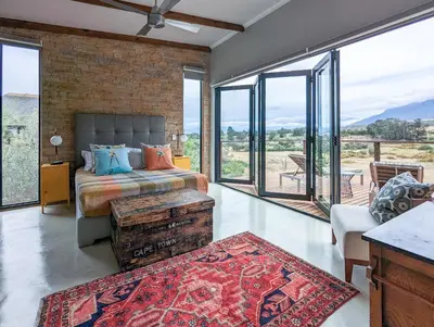 a bedroom with a bed and large windows at Tulbagh Mountain Bungalow in Wolseley